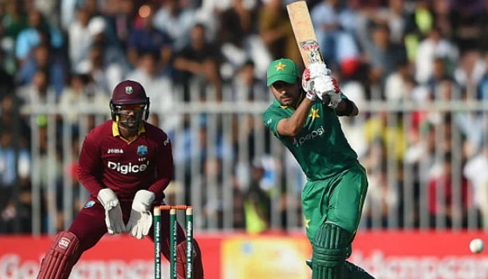A file photo of Babar Azam hitting a shot as a West Indies wicketkeeper looks on.