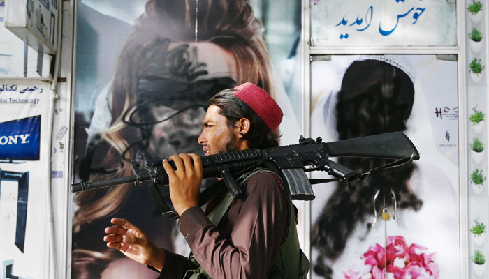 A Taliban fighter walks past a beauty saloon with images of women defaced using a spray paint in Shar-e-Naw in Kabul on August 18, 2021. &mdash; AFP/File