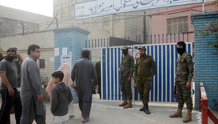 Security officials standing alert outside a polling station to avoid any untoward situation during by-elections of the NA-133 constituency, in Lahore, on December 5, 2021. — APP photo by Ashraf Chaudhry