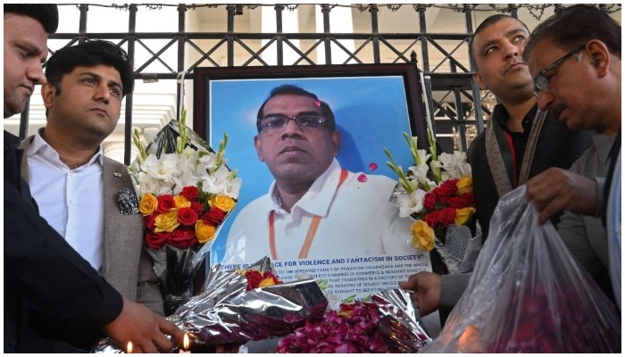 Some men lay flowers beside deceased Diyawadanage Don Nandasiri Priyanthas portrait. Photo: AFP