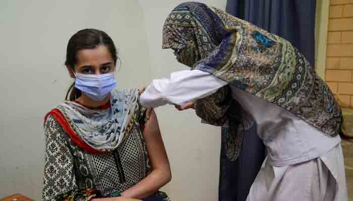 A lady health worker administering vaccine to a female. &mdash; Unicef