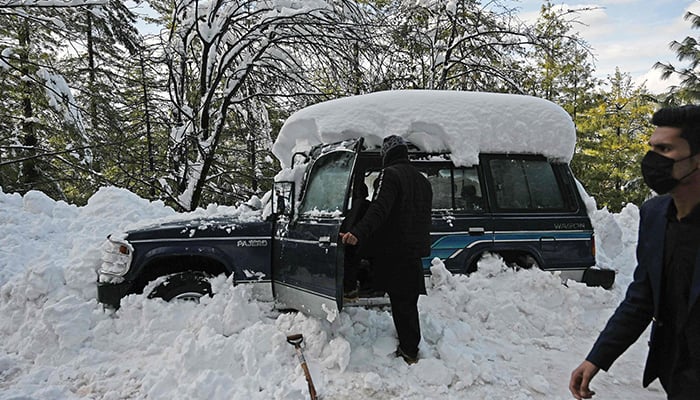 A tourist removes snow from his vehicle stucked on a road following a blizzard that started on January 7 which led to visitors being trapped in vehicles along the roads to the resort hill town of Murree, some 70 Kms northeast of Islamabad on January 9, 2022. &mdash; AFP/File