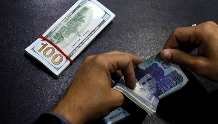 A currency dealer counts Rs1,000 notes while a stack of $100 notes is kept on the table. — Reuters/File