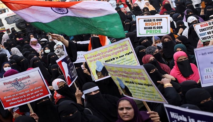 A woman waves the Indian flag as others hold placards during a protest against the recent hijab ban in schools in Karnataka state, on the outskirts of Mumbai, India, on February 13, 2022.&mdash;Reuters