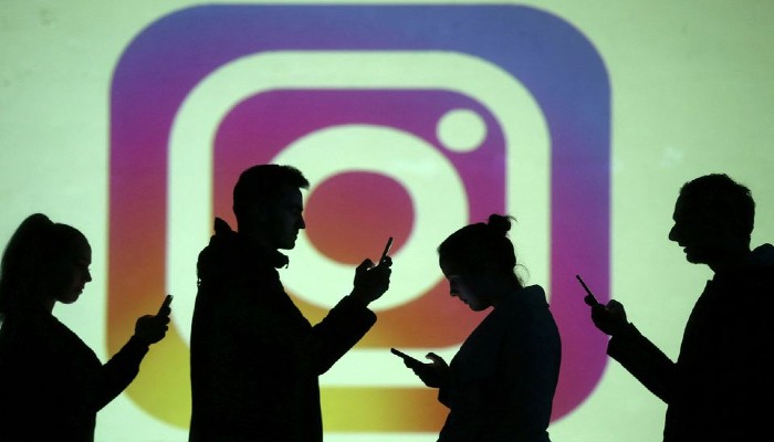 Silhouettes of mobile users are seen next to a screen projection of Instagram logo in this picture illustration taken March 28, 2018.Photo— REUTERS/Dado Ruvic/Illustration