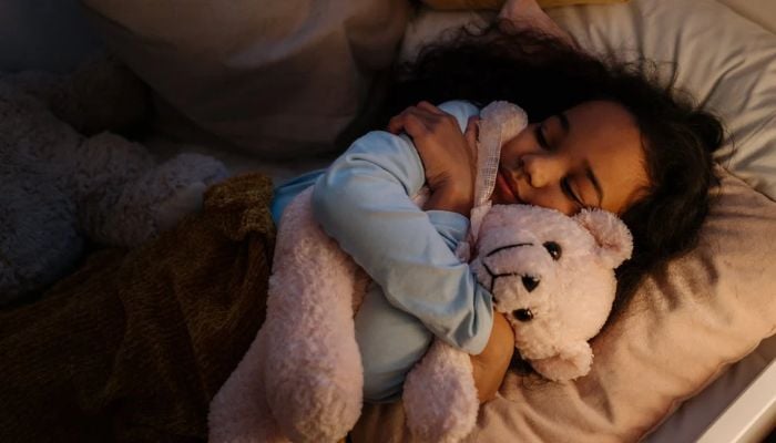 A girl sleeping with her teddy bear. &mdash; Unsplash