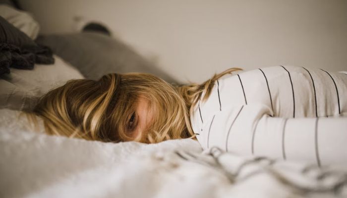 A woman lies on her front with her hair covering her face. &mdash;Unsplash