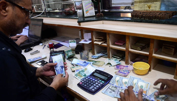 People exchange foreign currency at a shop in Karachi on April 7, 2022. &mdash; AFP
