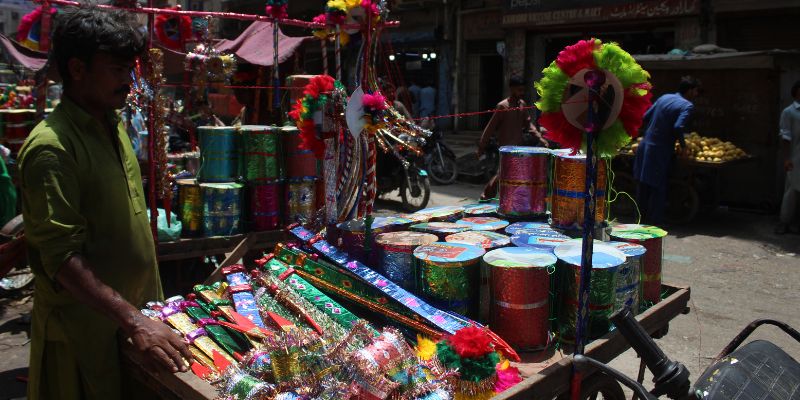 Kishan awaits customers while standing beside his toy cart in Kharadar - Image by author