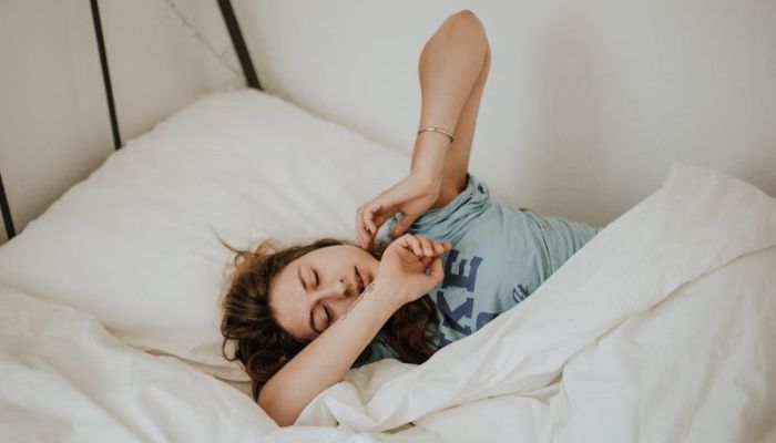 Woman lies on bed. Photo: Unsplash