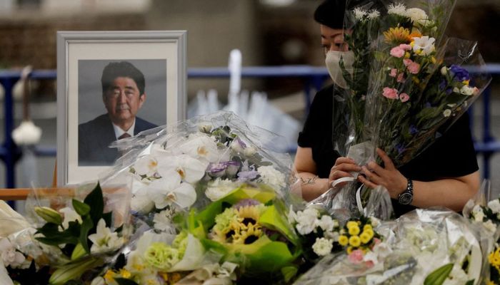 A mourner offers flowers next to a picture of late former Japanese Prime Minister Shinzo Abe, who was shot while campaigning for a parliamentary election, on the day to mark a week after his assassination at the Liberal Democratic Party headquarters, in Tokyo, Japan July 15, 2022. &mdash; Reuters