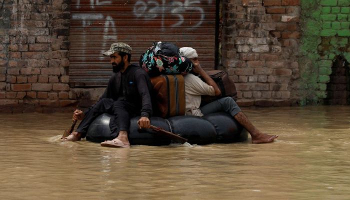 A volunteer paddles an inflatable tube as he evacuates a flood victim with his belongings, following rains and floods during the monsoon season in Charsadda.&mdash; Reuters