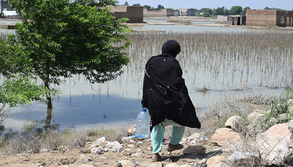 In this picture taken on September 3, 2022, Shameen Bibi, a flood-affected woman goes for toilet near a makeshift camp in Fazilpur, Rajanpur district of Punjab province. — AFP