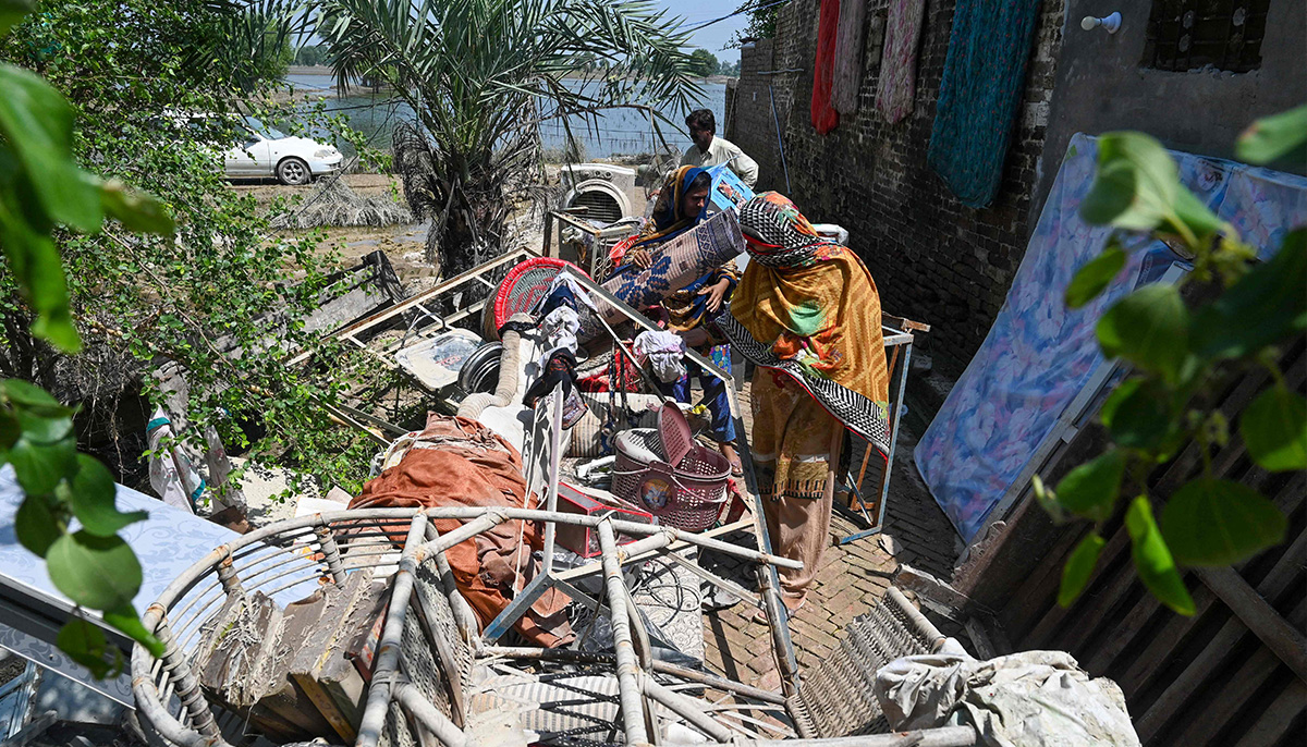 Mureed Hussain helps other family members to dry the dowry belongings of his daughter Nousheen, which were damaged by flood waters at his house in Fazilpur, Rajanpur district of Punjab province on September 3. &mdash; AFP