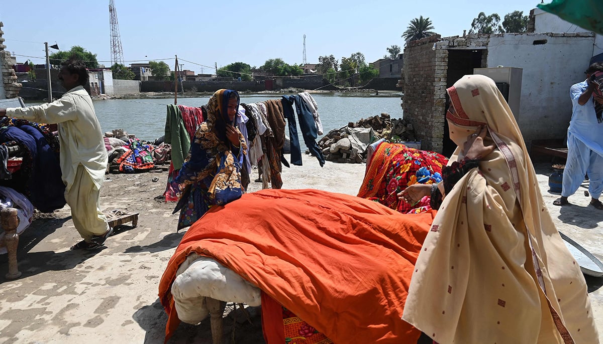 Mureed Hussain helps other family members to dry the dowry belongings of his daughter Nousheen, which was damaged by flood waters at his house in Fazilpur, Rajanpur district of Punjab province on September 3, 2022. &mdash; AFP
