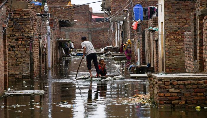 A man and a girl use a makeshift raft as they cross a flooded street, following rains during the monsoon season in Hyderabad, Pakistan August 24, 2022. — Reuters