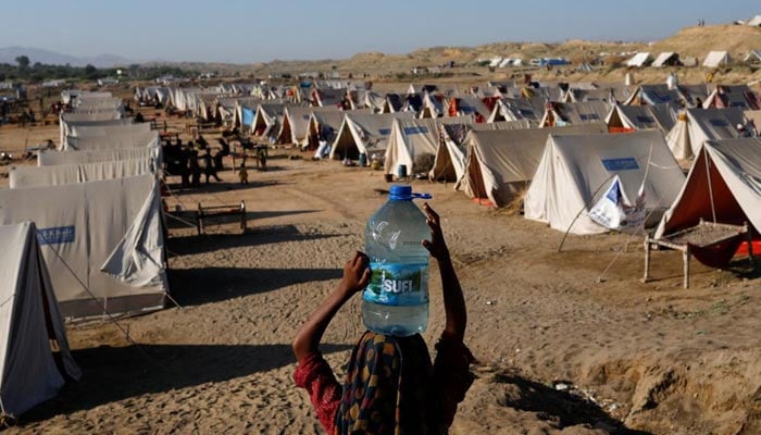 A displaced girl carries a bottle of water she filled from nearby stranded flood-waters, as her family takes refuge in a camp, in Sehwan, Pakistan, September 30, 2022. — Reuters