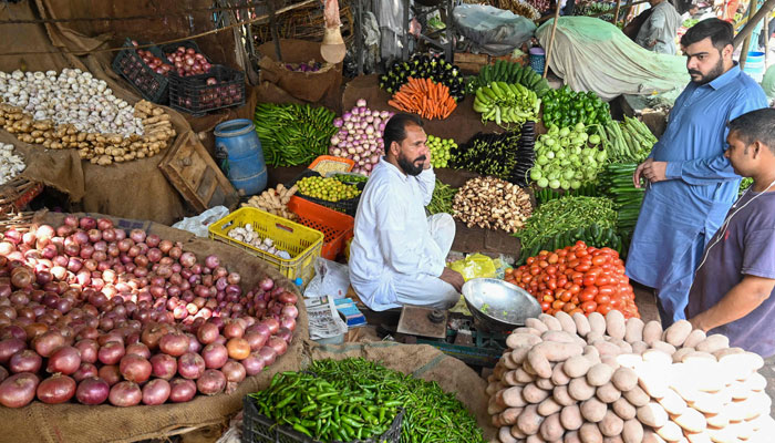 People buy vegetables at a local market in Lahore on August 29, 2022, amid a big hike in prices of food items in the wake of massive floods in Pakistan. — AFP/File