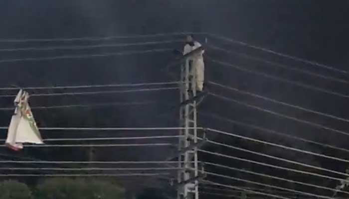 Screengrab from a video of the PTI worker climbing up an electric pole on Rawalpindis Murree Road, on November 7, 2022. — Twitter