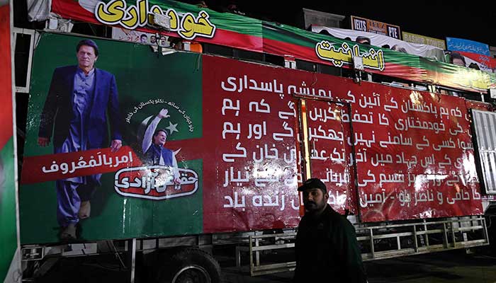 A police officer stands guard in front of container truck used by the former Pakistani prime minister Imran Khan during his political rallies, hours after a gun attack in Wazirabad on November 3, 2022. — AFP