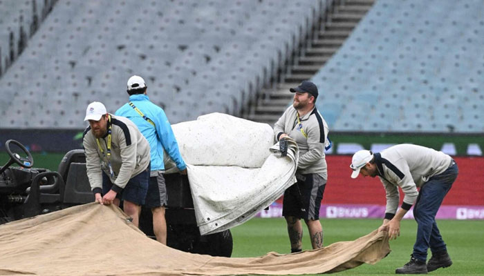 Groundmen cover the pitch area as rain delays the game between England and Ireland at the Melbourne Cricket Ground (MCG) on October 26. — AFP