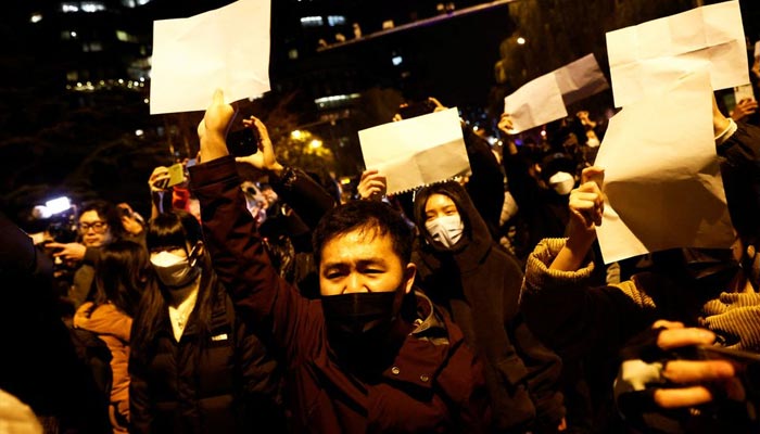 People gather for a vigil and hold white sheets of paper in protest of coronavirus disease (COVID-19) restrictions, as they commemorate the victims of a fire in Urumqi, as outbreaks of the coronavirus disease continue in Beijing, China, November 27, 2022. — Reuters