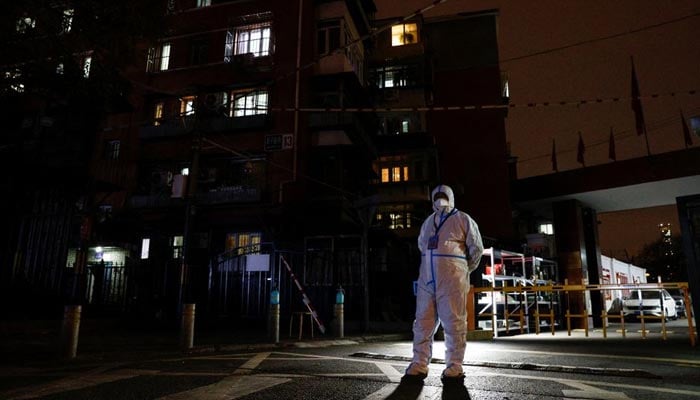 An epidemic prevention worker in a protective suit stands guard at the gate of a residential compound as outbreaks of the coronavirus disease (COVID-19) continue in Beijing, China November 27, 2022. — Reuters