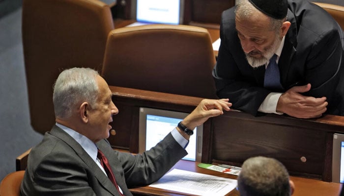 Israeli prime minister-designate Benjamin Netanyahu speaks with parliament member Aryeh Deri of the ultra-orthodox religious party Shas on December 13, 2022 — AFP/File