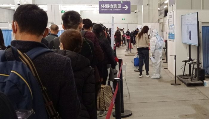 Passengers arriving on international flights wait in line next to a police officer wearing personal protective equipment (PPE) and speaking with a woman at the airport in Chengdu, China January 6, 2023.— Reuters
