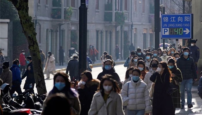 As the COVID-19 outbreaks continue, people wearing face masks photographed while walking on a street in Shanghai on December 13, 2022. — Reuters