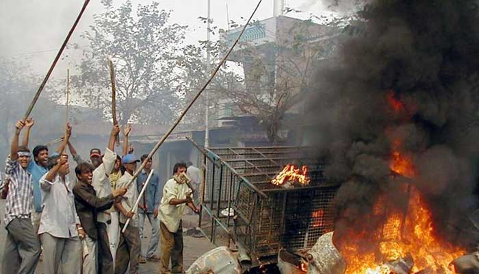 Indian rioters wave sticks as they stand next to a bonfire on the streets of Ahmedabad, the main city of the Western state of Gujarat February 28, 2002. — Reuters/File