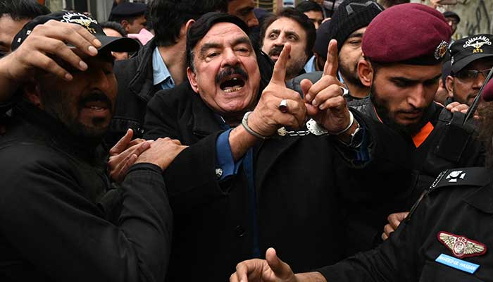 Police officials escort former interior minister Sheikh Rashid Ahmed (centre) to present him before a court in Islamabad on February 2, 2023. — AFP/File