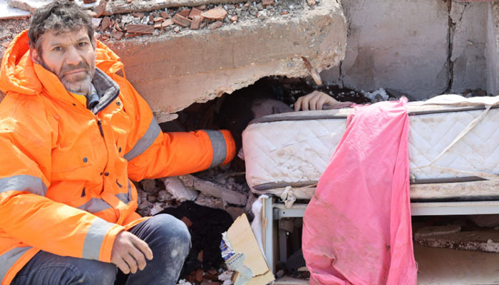 Mesut Hancer holds the hand of his 15-year-old daughter Irmak, who died in the earthquake in Kahramanmaras, close to the quake´s epicentre, the day after a 7.8-magnitude earthquake struck the country´s southeast, on February 7, 2023. AFP