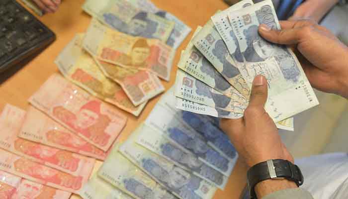 A money changer counts Pakistans currency at a market in Karachi on January 6, 2023. — AFP/File