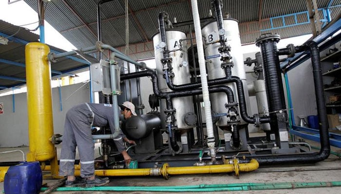A worker drains water from a gas filter at the Egas processing plant in Gujar Khan, Pakistan. — Reuters/File