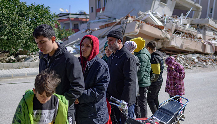 Residents wait in a queue outside a bakery that gives out free bread in Samandag, south of Hatay, Turkey on February 16, 2023.— AFP