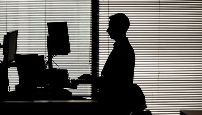 A man works at a computer on a standing desk in an office in the financial district of Canary Wharf in London, Britain, February 8, 2023.— Reuters