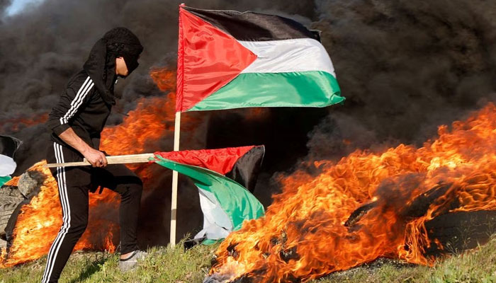 A man holds a flag as Palestinians clash with Israeli forces near the Israel-Gaza border, east of Gaza City, February 22 2023.— Reuters