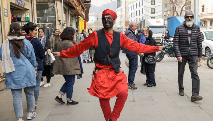 An Iranian man dressed as the fictional folklore character Hajji Firuz performs on at a street in Tehran ahead of the Nowruz New Year festival. — AFP/File