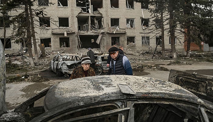 An eldery couple looks at a burnt car in front of a destroyed building after a deadly strike in the city of Sloviansk, on March 27, 2023. Shelling of the eastern Ukraine town of Sloviansk on March 27, 2023, killed at least two people and wounded more than two dozen others, authorities said.—AFP