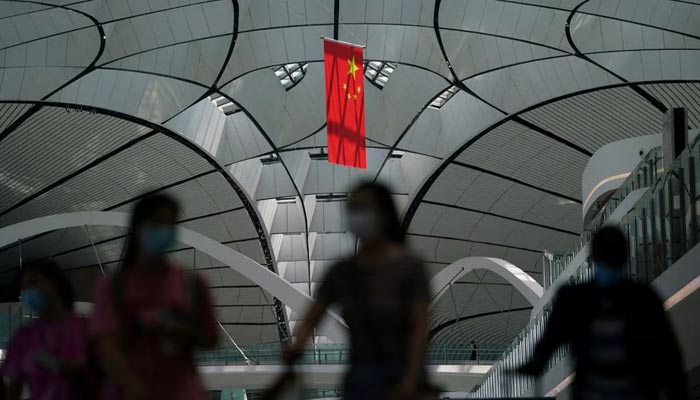 People wearing face masks following the coronavirus disease (COVID-19) outbreak walk under a Chinese flag at Beijing Daxing International Airport in Beijing, China July 24, 2020. — Reuters