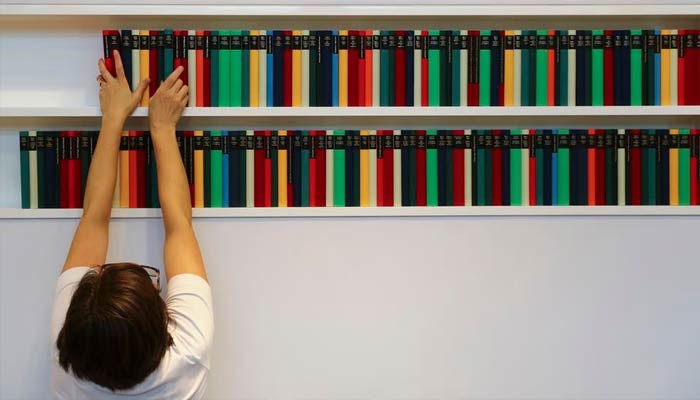 This file photo shows a woman arranging books in a shelf. — Reuters