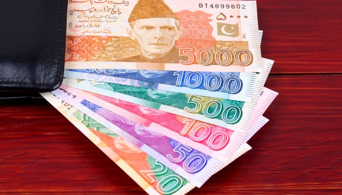 An undated image of Pakistani notes peeking out from a black wallet. &mdash; Canva