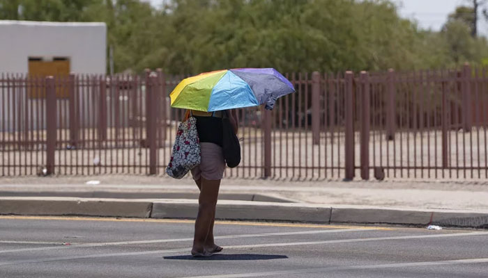 A woman shields herself from the sun with an umbrella during a heatwave in Tucson, Arizona, on July 15, 20223. — AFP