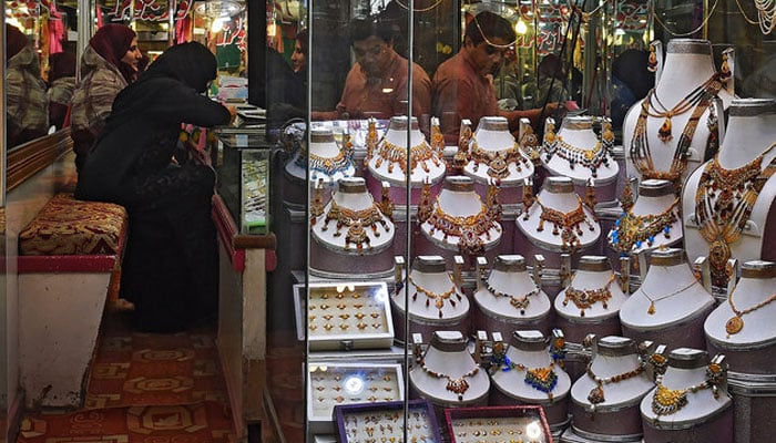 Pakistani women check gold jewellery at a shop in Lahore, Pakistan, on October 11, 2018. — AFP