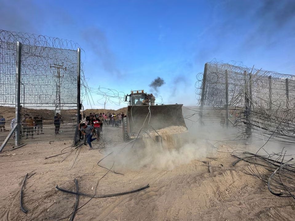 Palestinians break into the Israeli side of the Israel-Gaza border fence after gunmen infiltrated areas of southern Israel, October 7, 2023. — Reuters