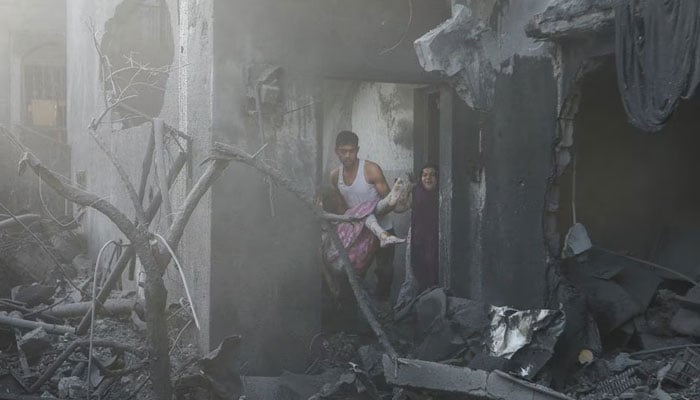 A man carries a wounded Palestinian girl at the site of Israeli strikes on a house, in Khan Younis in the southern Gaza Strip, October 11, 2023. — Reuters