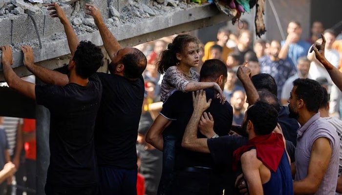 A Palestinian carries a child casualty at the site of an Israeli strike on a house, in Khan Younis, in the southern Gaza Strip, October 24.—Reuters