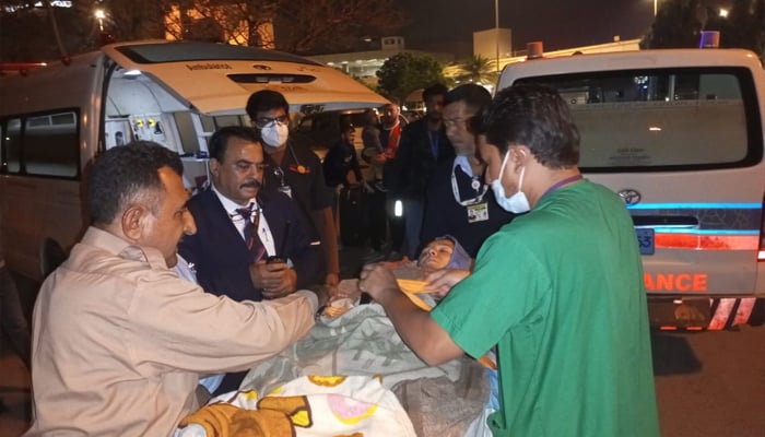 Roshan Bibi being moved into an ambulance at Karachi airport to be shifted to a hospital for treatment. — reporter