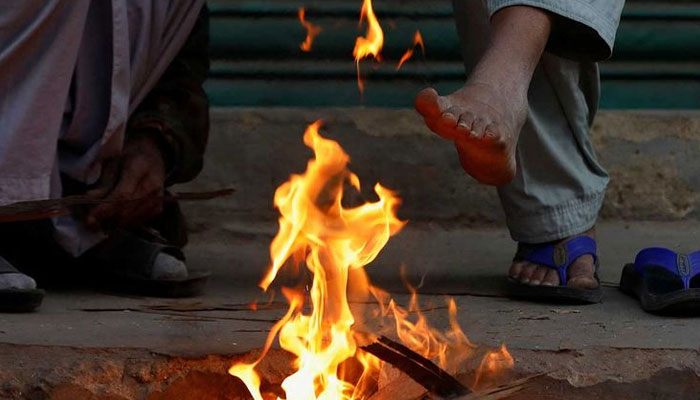 Labourers keep themselves warm near a fire during a cold morning in Karachi on January 13, 2023.  —Reuters